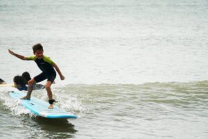 Young surfer in a wetsuit balancing on a green surfboard, Easter Surfkid Camp at Lower Cheung Sha