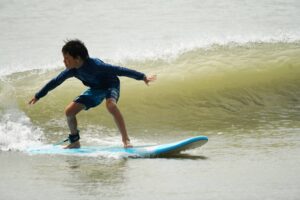 Boy in a full wetsuit dropping into a wave, Winter Surfkid Camp Hong Kong