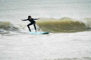 Girl in a wetsuit surfing a wave at Lower Cheung Sha Beach, Easter Surfkid Camp