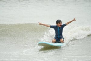 Kid with arms out balancing on a surfboard, Easter Surfkid Camp at Lower Cheung Sha Beach